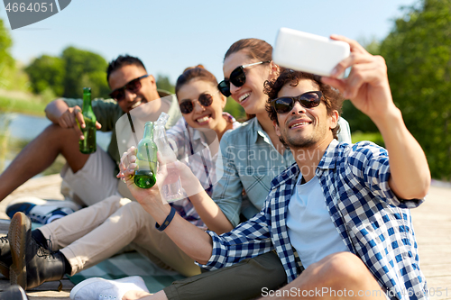 Image of friends with drinks taking selfie by smartphone