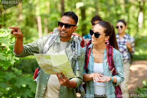 Image of friends with map and backpacks hiking in forest