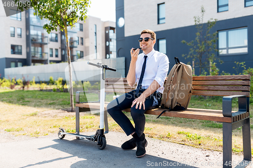 Image of businessman recording voice message by smartphone