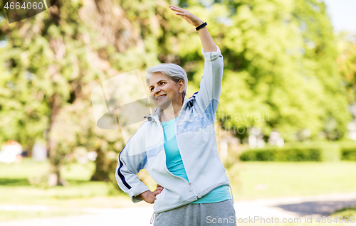 Image of happy senior woman exercising at summer park