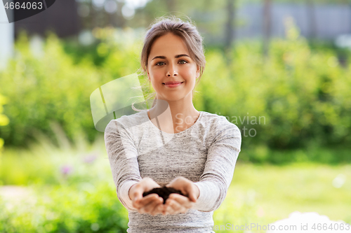 Image of young woman with handful of soil at summer garden