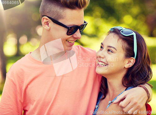Image of happy teenage couple looking at each other in park
