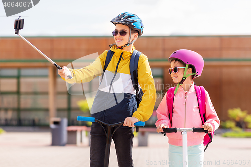 Image of happy school kids with scooters taking selfie