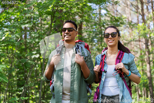 Image of mixed race couple with backpacks hiking in forest