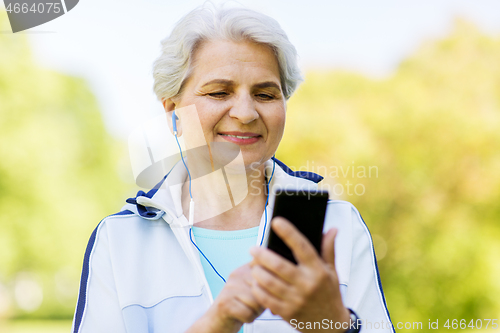 Image of sporty senior woman with earphones and smartphone