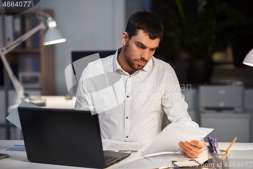 Image of businessman with papers working at night office