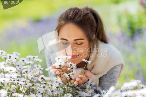 Image of close up of woman smelling chamomile flowers