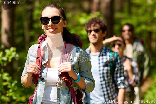 Image of group of friends with backpacks hiking in forest