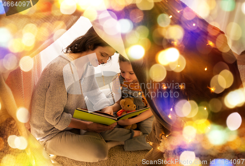 Image of happy family reading book in kids tent at home