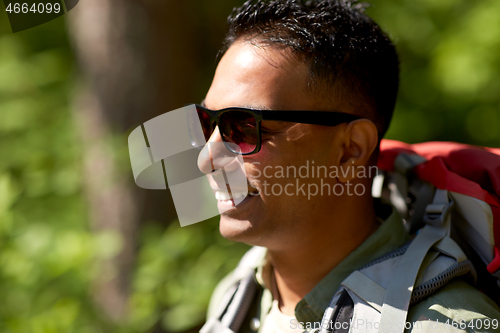 Image of happy indian man with backpack hiking in forest