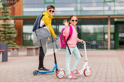 Image of school children with backpacks riding scooters