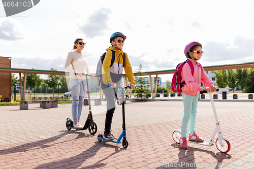Image of happy school children with mother riding scooters