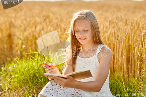 Image of smiling girl writing to diary on cereal field