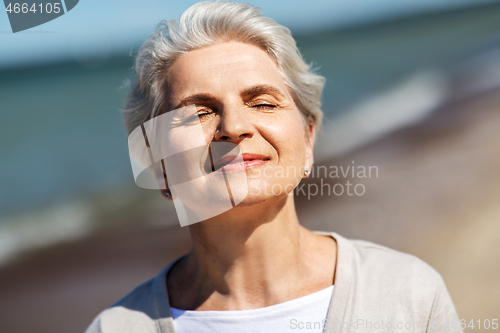 Image of portrait of senior woman enjoying sun on beach