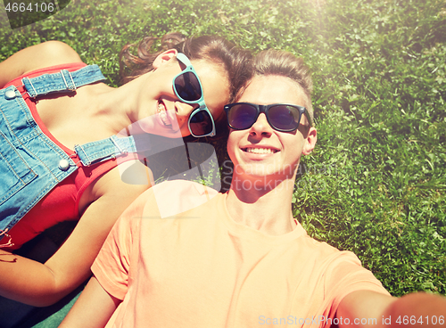 Image of happy teenage couple taking selfie on summer grass