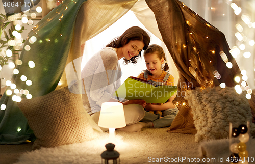 Image of happy family reading book in kids tent at home