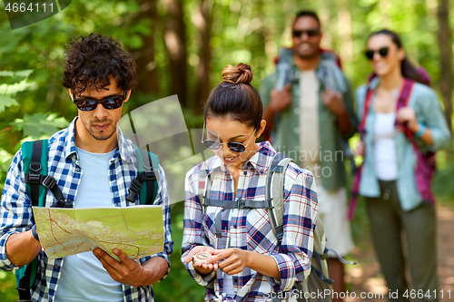 Image of friends with map and backpacks hiking in forest