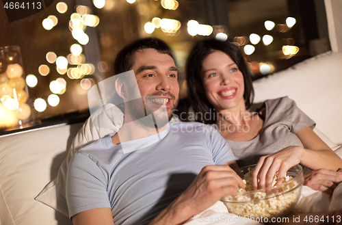 Image of couple with popcorn watching tv at night at home