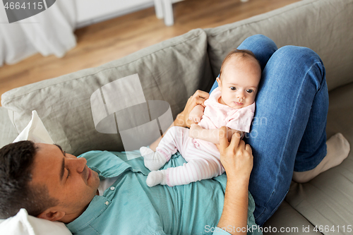 Image of middle aged father with baby lying on sofa at home