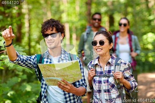 Image of friends with map and backpacks hiking in forest