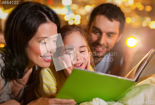 Image of happy family reading book in bed at night at home