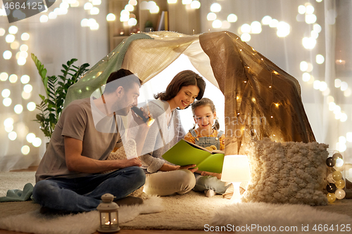 Image of happy family reading book in kids tent at home