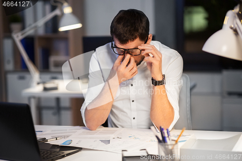 Image of tired businessman working at night office