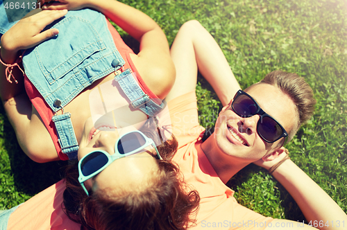 Image of happy teenage couple lying on grass at summer