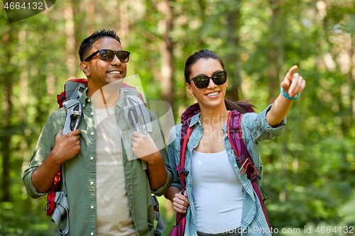 Image of mixed race couple with backpacks hiking in forest