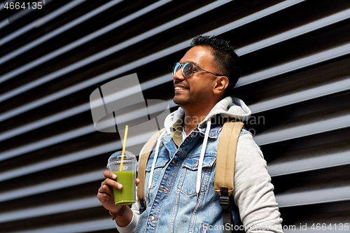 Image of man with backpack drinking smoothie on street