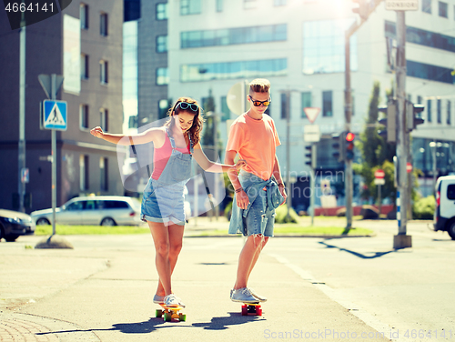 Image of teenage couple riding skateboards on city street