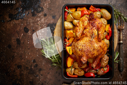 Image of Whole roasted chicken or turkey with pumpkin, potatoes, red pepper and rosemary.