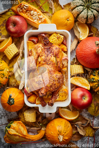 Image of Thanksgiving dinner table with roasted whole chicken or turkey, pumpkin, baked potatoes, chestnuts