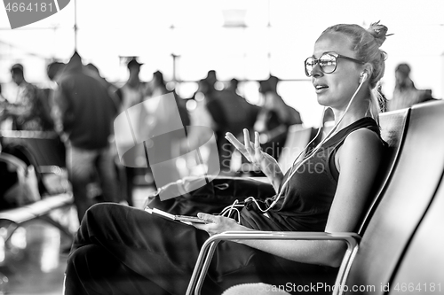 Image of Female traveler talking on cell phone while waiting to board a plane at departure gates at asian airport terminal.