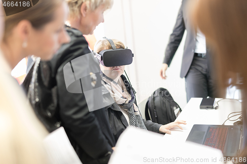 Image of Unrecognizable woman wearing virtual reality headset glasses on virtual reality trade show business conference presentation