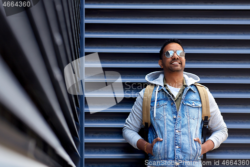 Image of smiling indian man with backpack on city street