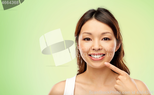 Image of happy smiling young asian woman touching her face