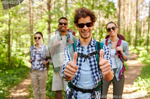 Image of friends with backpacks showing thumbs up in forest