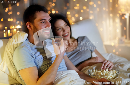 Image of couple with popcorn watching tv at night at home