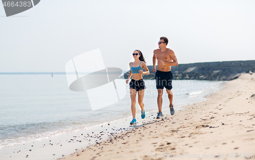 Image of couple in sports clothes running along on beach