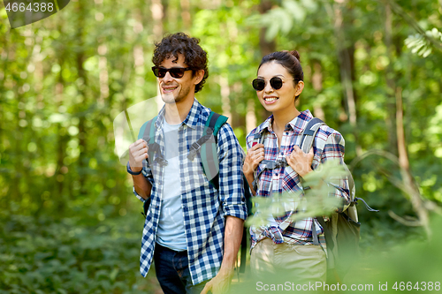 Image of mixed race couple with backpacks hiking in forest