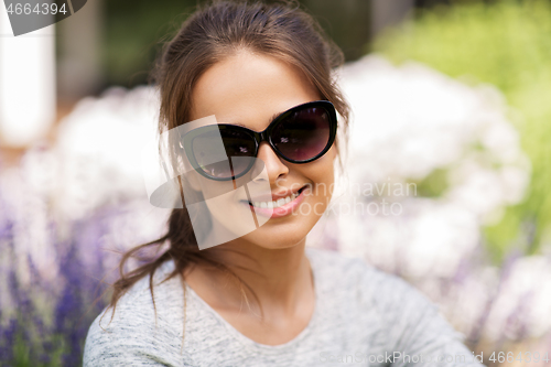 Image of happy young woman in sunglasses at summer garden