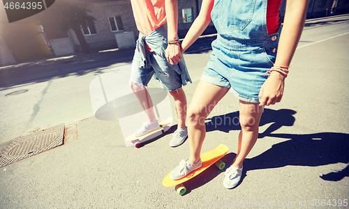 Image of teenage couple riding skateboards on city street