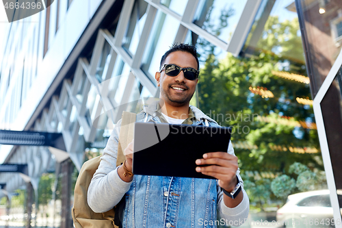 Image of man with tablet pc and backpack on city street