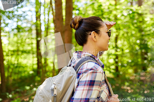 Image of happy asian woman with backpack hiking in forest