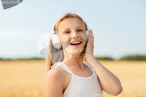 Image of happy girl in headphones on cereal field in summer