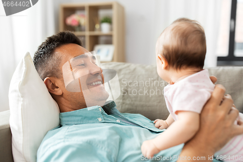 Image of middle aged father with baby lying on sofa at home