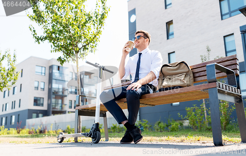 Image of businessman with scooter drinking coffee in city