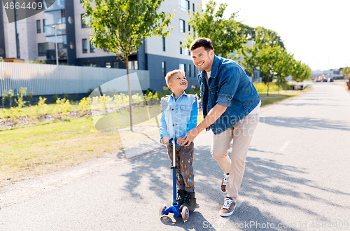 Image of happy father and little son riding scooter in city