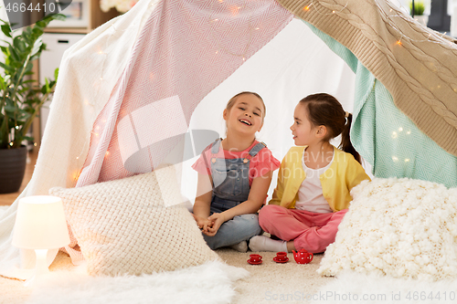 Image of little girl playing tea party in kids tent at home